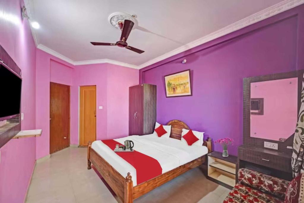 a bedroom with purple walls and a bed and a tv at Hotel GRG Varanasi Paradise Varanasi in Varanasi