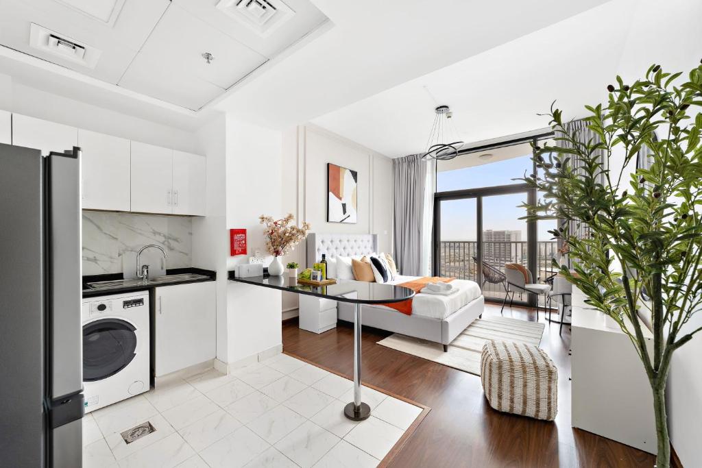 a white kitchen and living room with a table at Silkhaus Modern Studio near Silicon Shopping Mall in Dubai