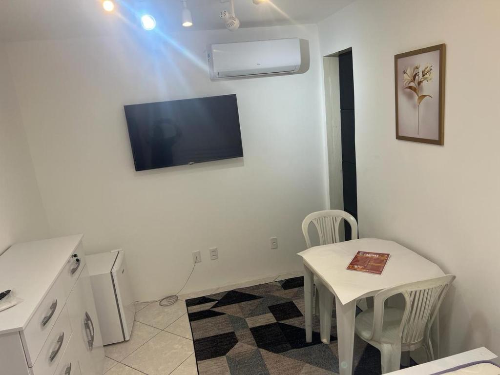 Dieses weiße Zimmer verfügt über einen Tisch und einen TV an der Wand. in der Unterkunft Suite 1, Casa Amarela, Segundo Andar in Nova Iguaçu