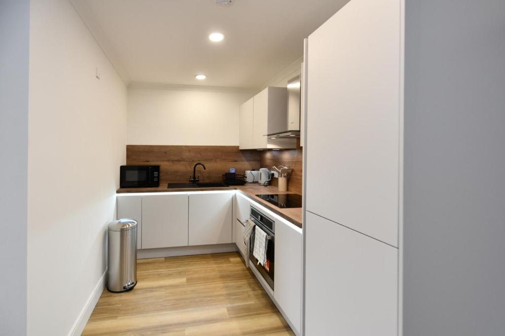a kitchen with white cabinets and wooden floors at Troon Portland Apt B in Troon