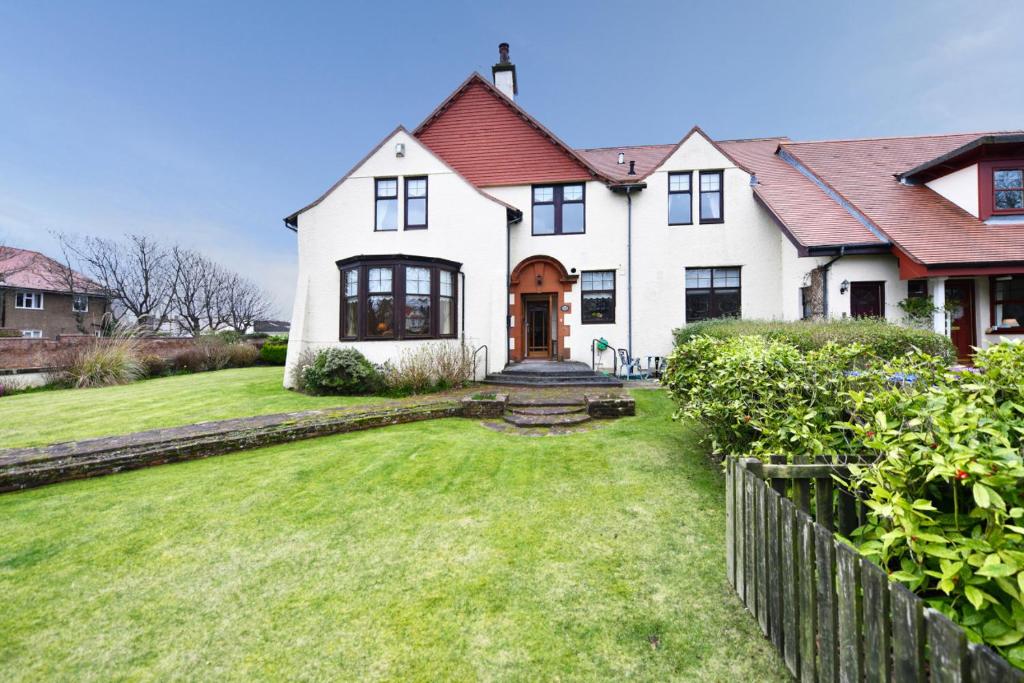 a large white house with a grass yard at Dunvegan Apartment Troon in Troon