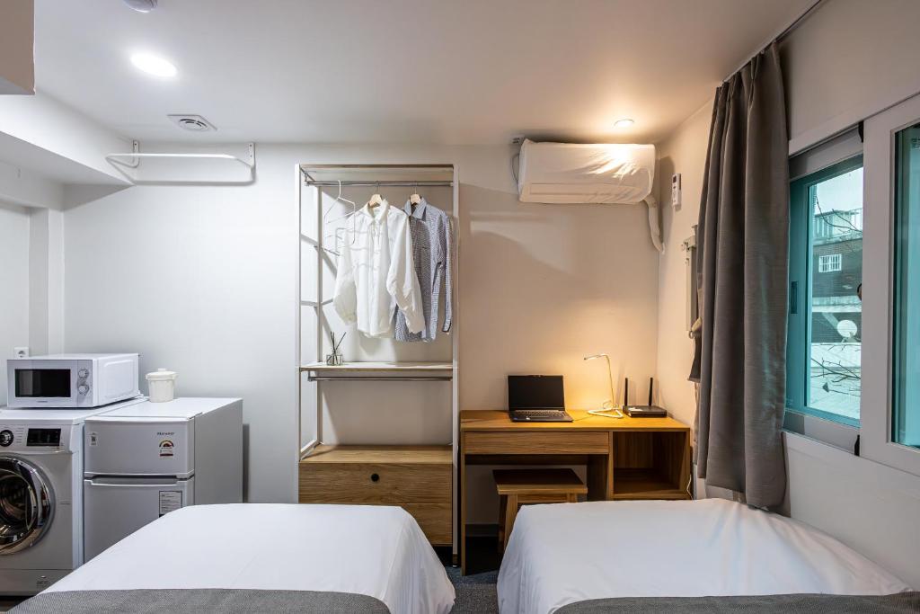 Habitación con 2 camas, escritorio y perchero. en K Stay 3rd Myeongdong City, en Seúl