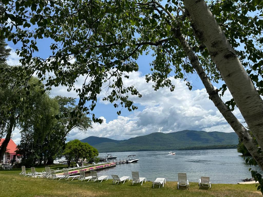 Eine Gruppe von Stühlen steht am Ufer eines Sees in der Unterkunft The Villas on Lake George in Diamond Point