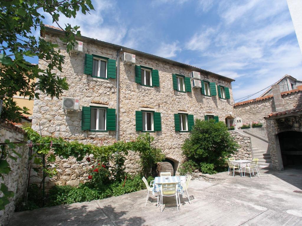 a stone building with green shuttered windows and tables at Malin Guesthouse in Skradin