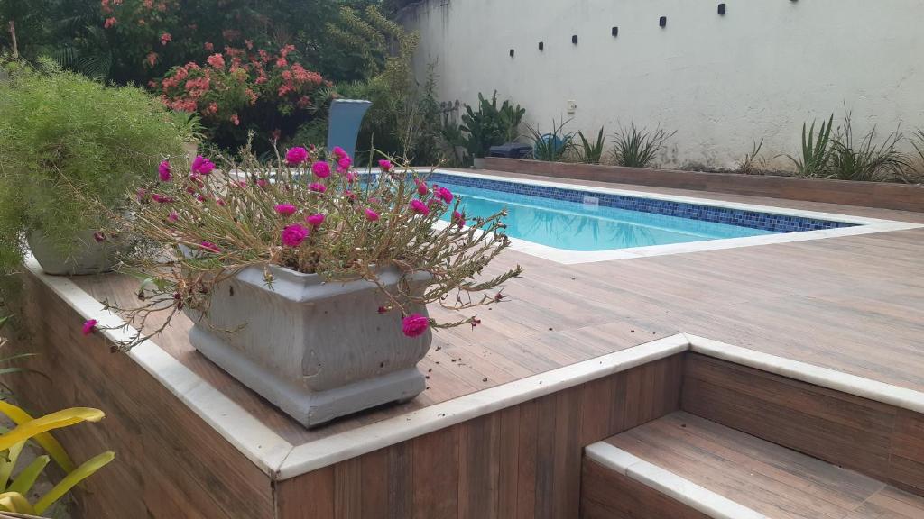 ein Pflanzer mit rosa Blumen neben einem Pool in der Unterkunft Casa Aconchegante in Saquarema