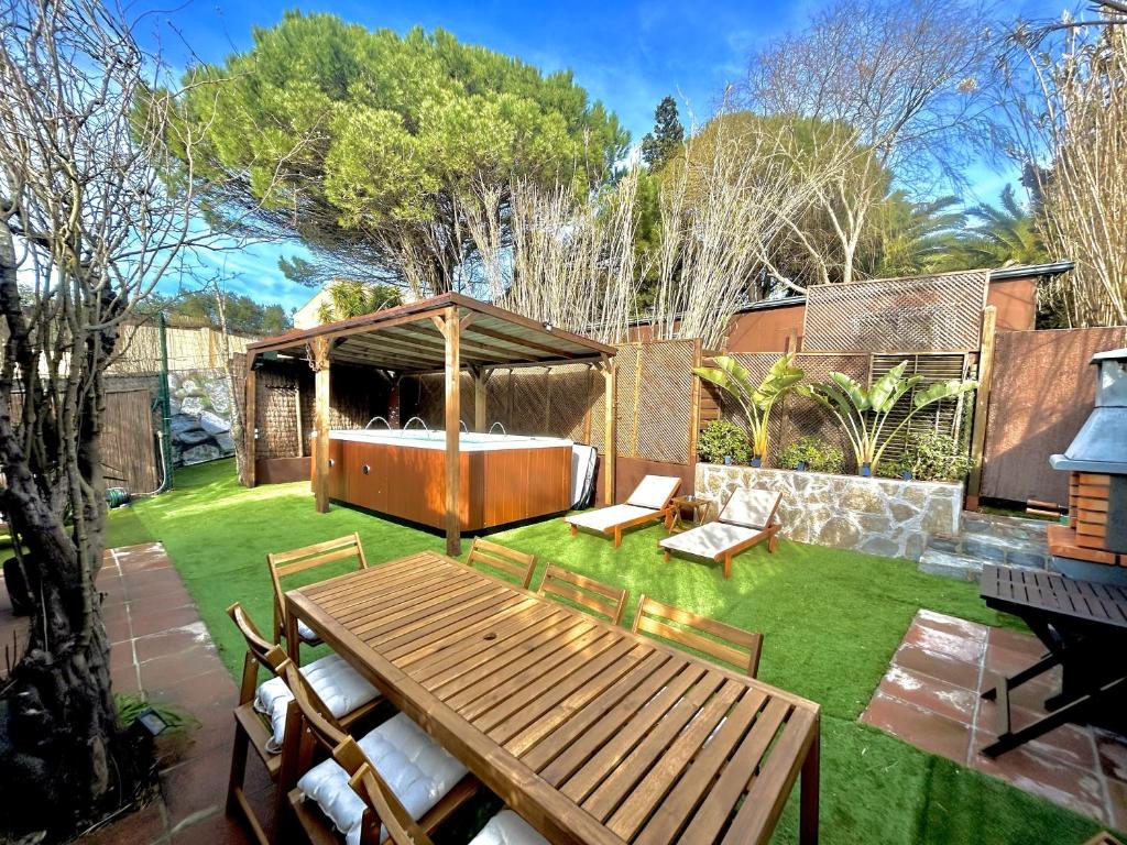 un patio trasero con una mesa de madera y un cenador en La Villa Verde, en Tarifa