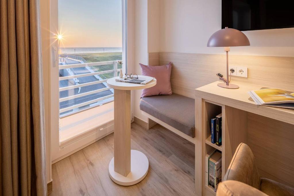 Zimmer mit einem Schreibtisch und einem Fenster mit einem Sofa in der Unterkunft Hotel Stranddistel in Norderney