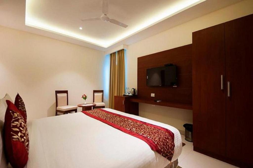 um quarto de hotel com uma cama e uma televisão em Prime Z Suites Hotel- Near Delhi International Airport em Nova Deli