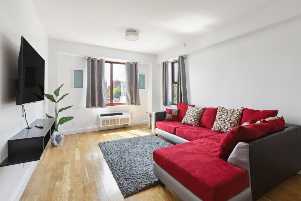 a living room with a red couch and a tv at Flat In The Bush in Brooklyn