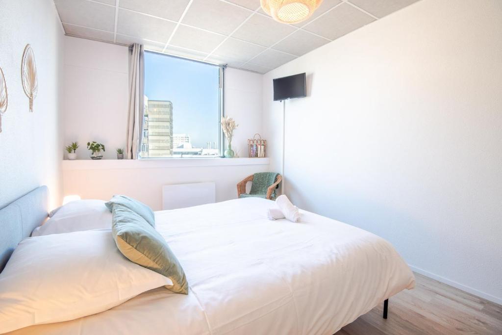 une chambre avec un lit blanc et une fenêtre dans l'établissement Appartement Le Cocooning, à Tours