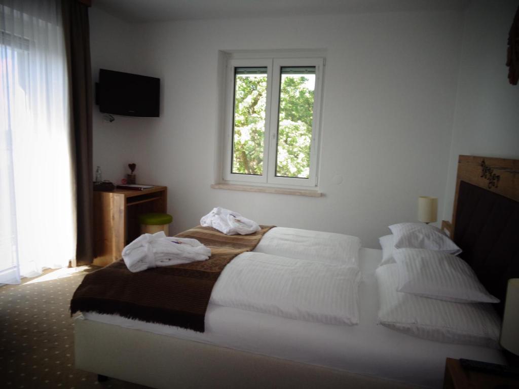 Schlafzimmer mit einem Bett mit weißer Bettwäsche und einem Fenster in der Unterkunft Familienhotel Berger in Sankt Jakob im Walde