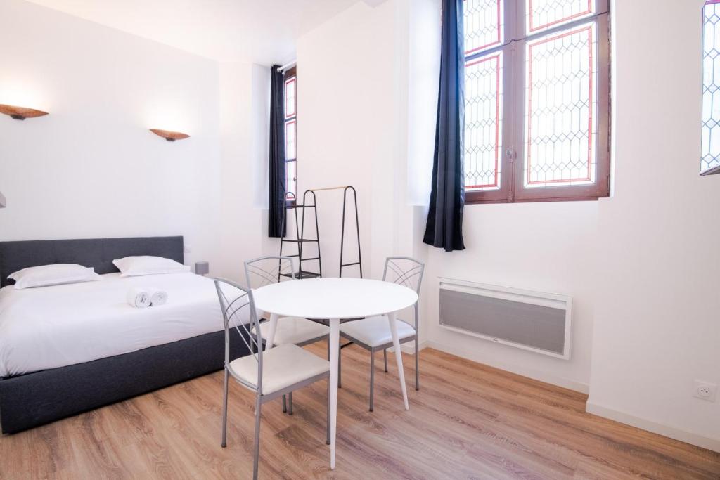 een slaapkamer met een bed en een tafel en stoelen bij My white paradise - fully equipped apartment in Tours