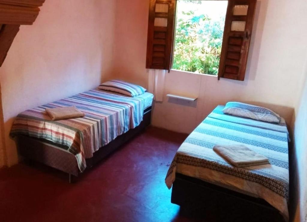 two beds in a room with two windows at Casa Quaresmeira in Palmeiras