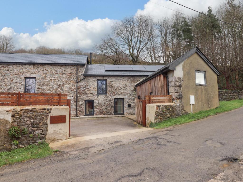 an old stone house with a barn and a driveway at 3 Caddaford Barns in Buckfastleigh