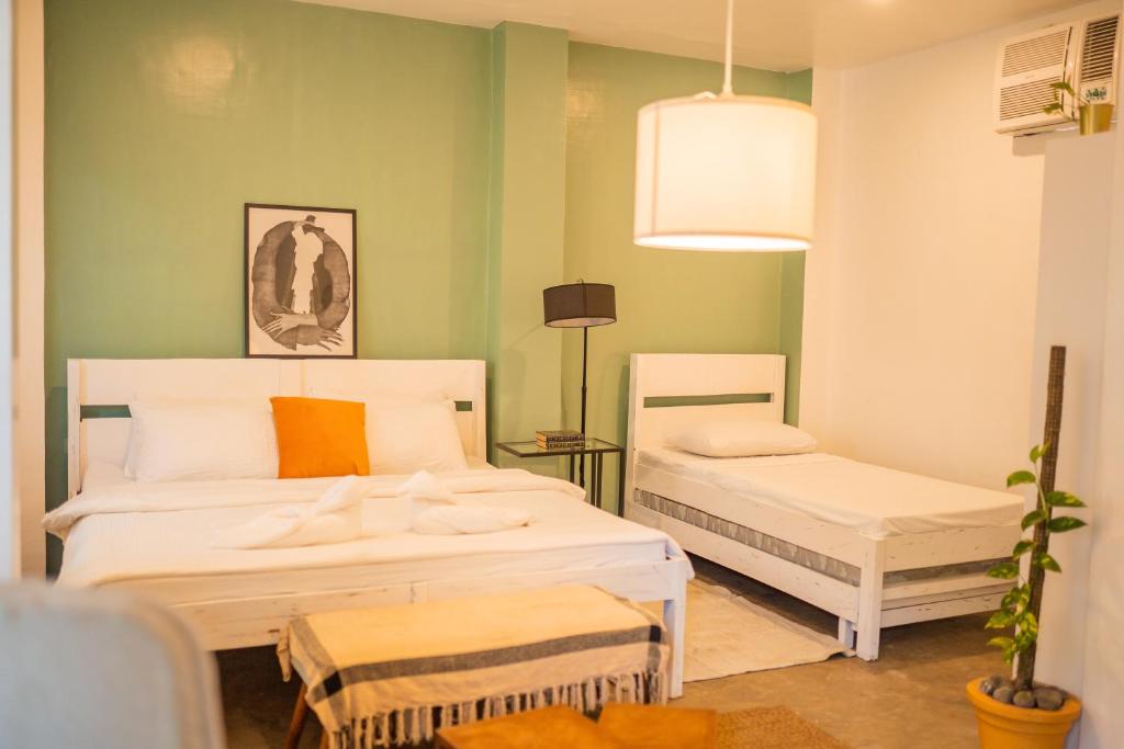 duas camas num quarto com paredes verdes em The Bard's Nest em General Luna