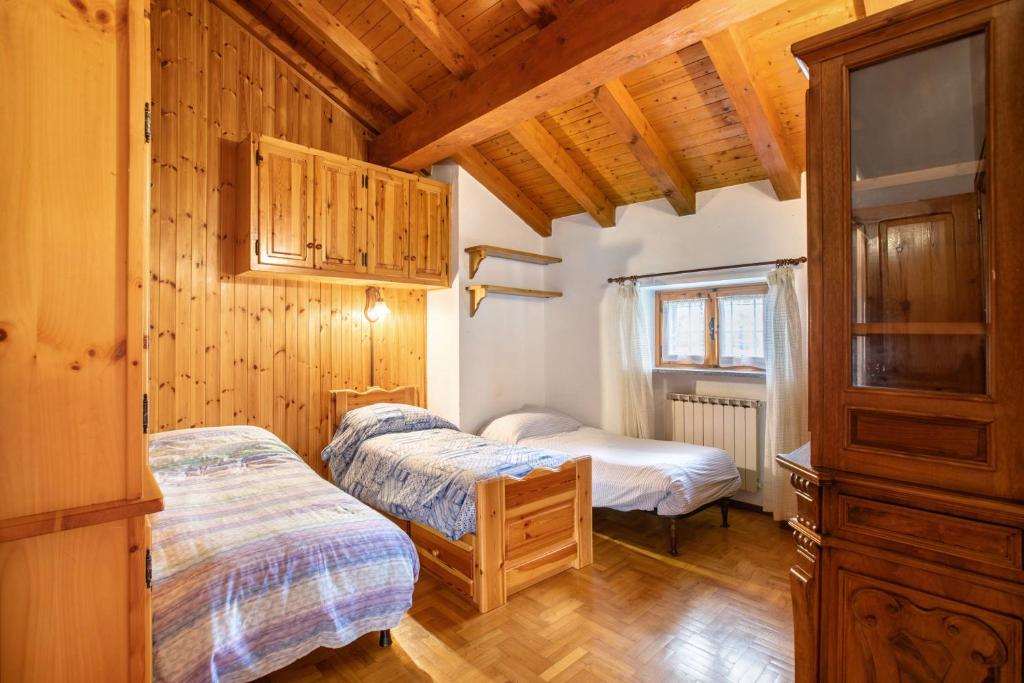 una camera con due letti in una stanza con pareti in legno di Casa Vacanza Menfrey a Verrayes