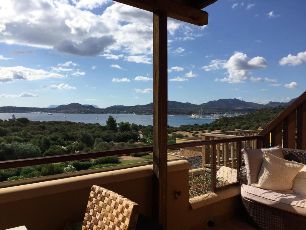 a balcony with a view of a lake and mountains at Smeralda Residenza Di Charme in Marina di Portisco