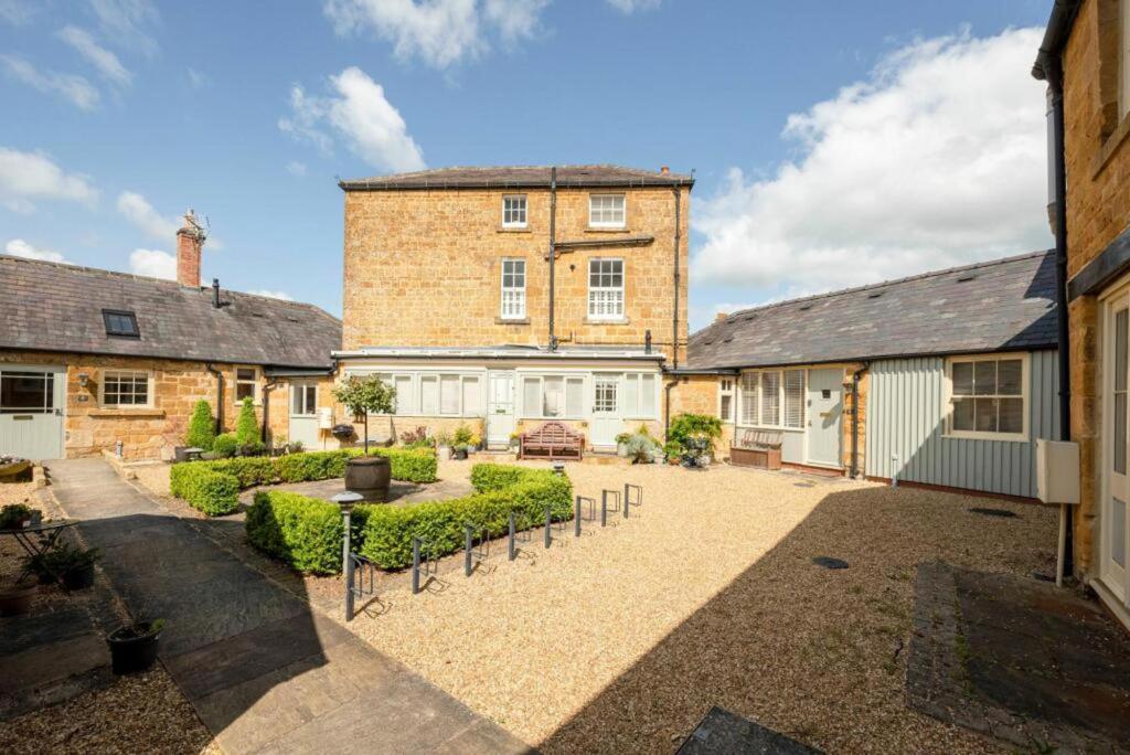 uma vista para o exterior de um grande edifício de tijolos com um pátio em Immaculate 1-Bed Cottage in Moreton in marsh em Moreton-in-Marsh