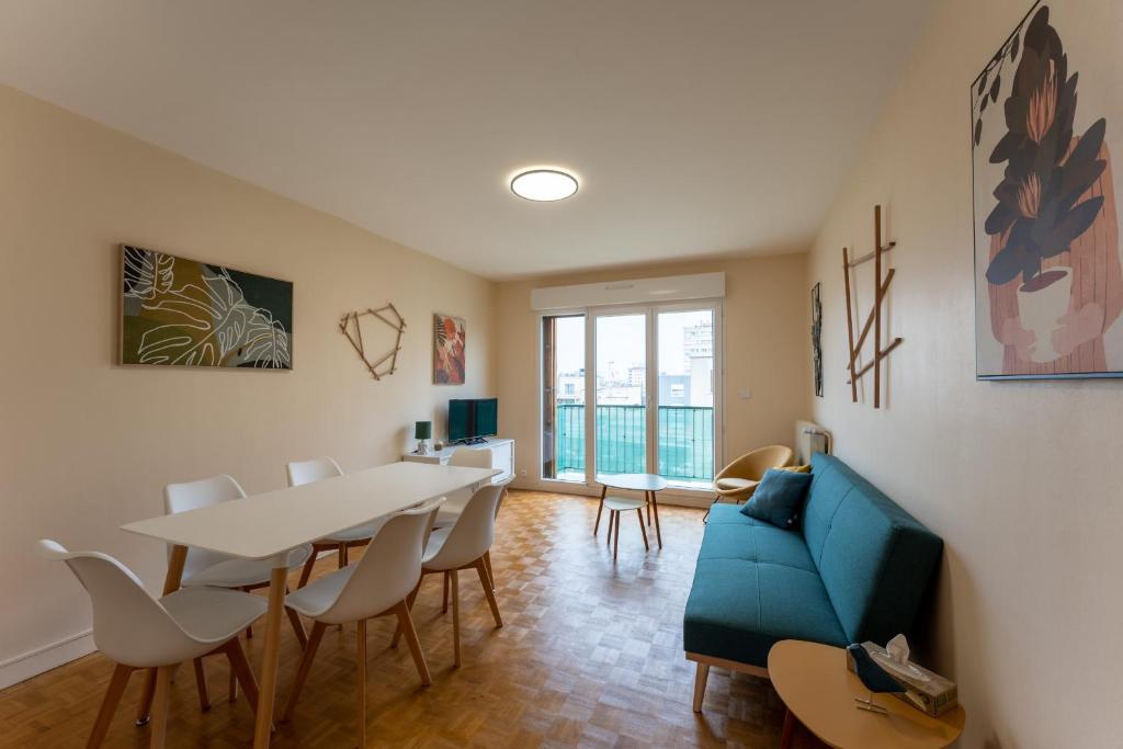 un salon avec une table et un canapé bleu dans l'établissement Appartement BONDY chaleureux - 2 chambres, à Bondy