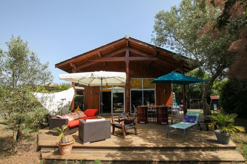 a patio with a couch and chairs and umbrellas at Maison familiale en bois proche du lac de Cazaux in La Teste-de-Buch