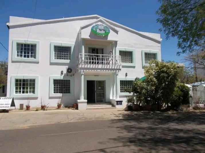 a white house with a clock on the front of it at Brakendene Lodge in Gaborone