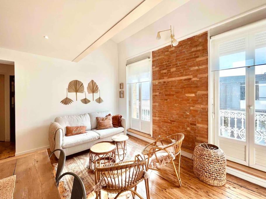 un salon avec un canapé et un mur de briques dans l'établissement La Terrasse Saint Sauveur, à Toulouse