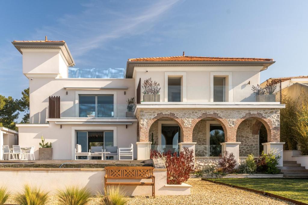 een wit huis met een bankje ervoor bij VILLA LA ROMANELLA in Carry-le-Rouet