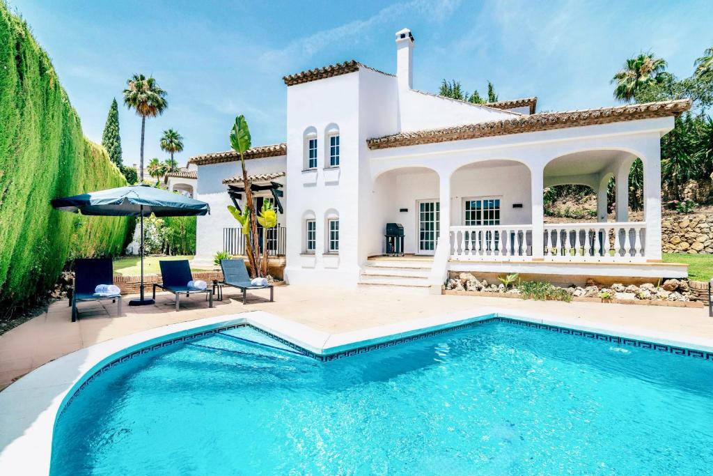 a villa with a swimming pool in front of a house at 4 bedroom Villa in Top location - Heating Pool in Marbella