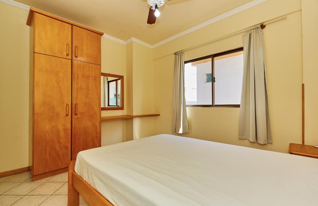 1 dormitorio con 1 cama, vestidor y ventana en 945 - Apartamento Ed Estrela do Mar II - Centro Bombinhas - Garagem para 1 Carro, en Bombinhas