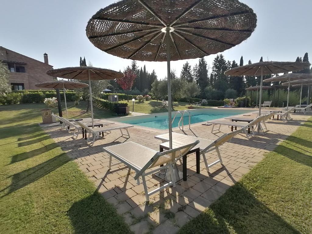 un groupe de tables et de parasols à côté d'une piscine dans l'établissement Agriturismo Carpineto, à Asciano