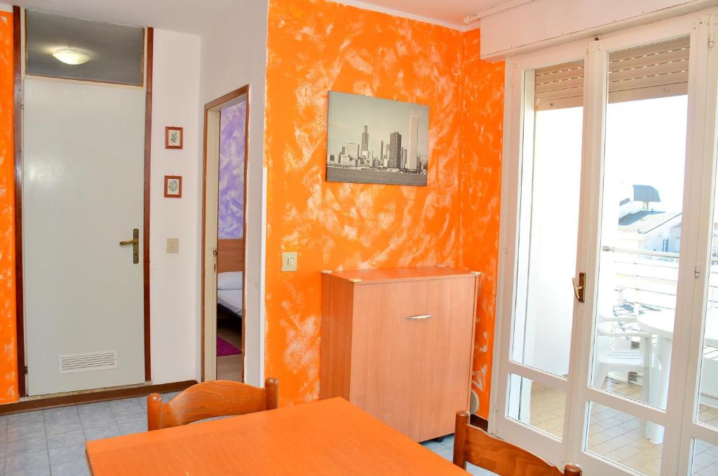 uma sala de jantar com uma parede laranja em Condominio Adriatico em Bibione