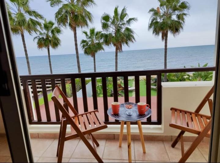 a table and chairs on a balcony with the ocean at Beachfront Villa Carpe Diem in Kiti
