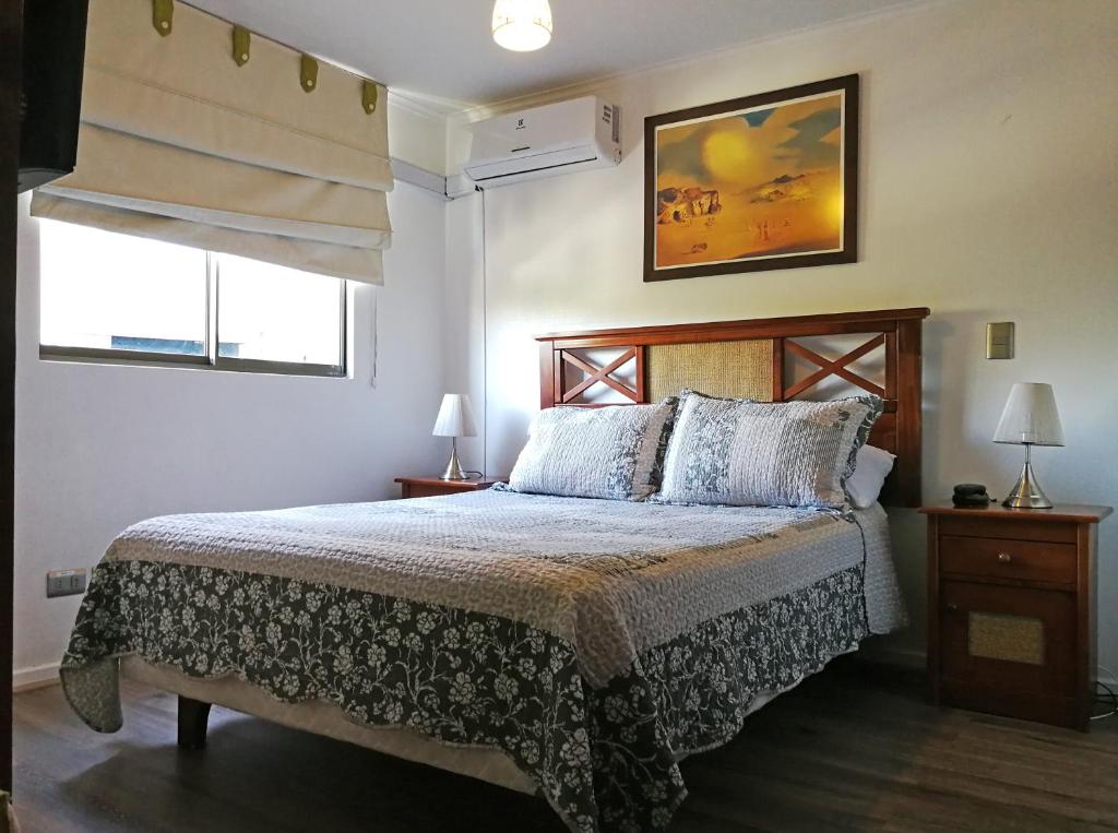 a bedroom with a bed and two windows at AMISTAR BELLAS ARTES in Santiago