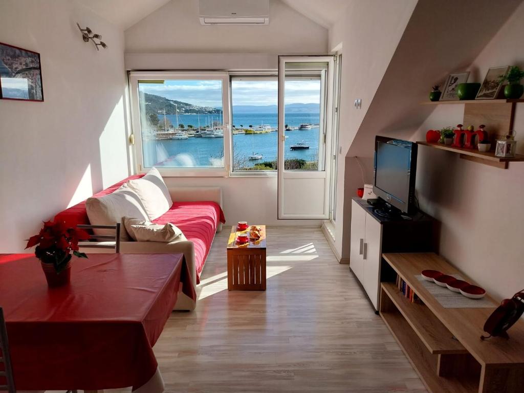 a living room with a red couch and a large window at Seaview apartment in Omiš