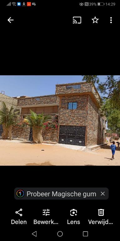 a picture of a brick building with a man standing in front of it at Maison Manour, chambre 'Tribal' in Mbour