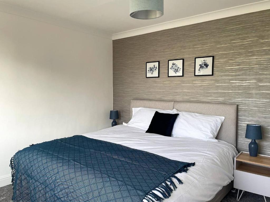 sypialnia z łóżkiem i 3 zdjęciami na ścianie w obiekcie Spacious 5-bed - Perfect For Contractors 
