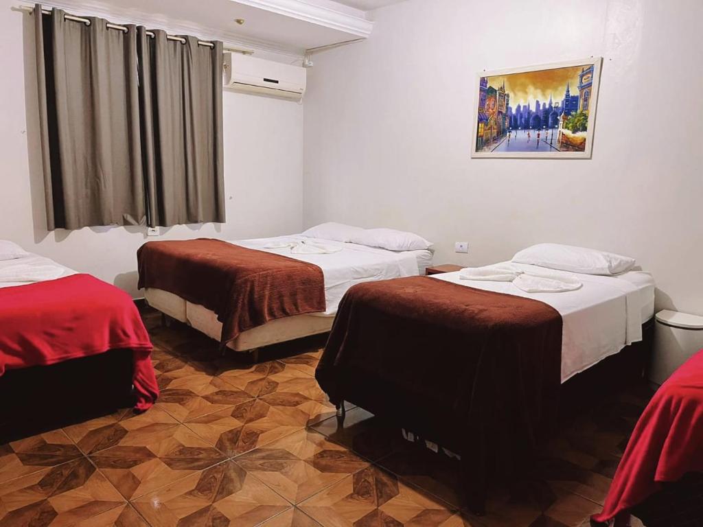 a room with two beds and a painting on the wall at Pousada da Maira in Foz do Iguaçu