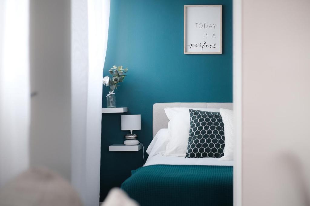 1 dormitorio con 1 cama con pared azul en Appartement cosy et calme, en Élancourt