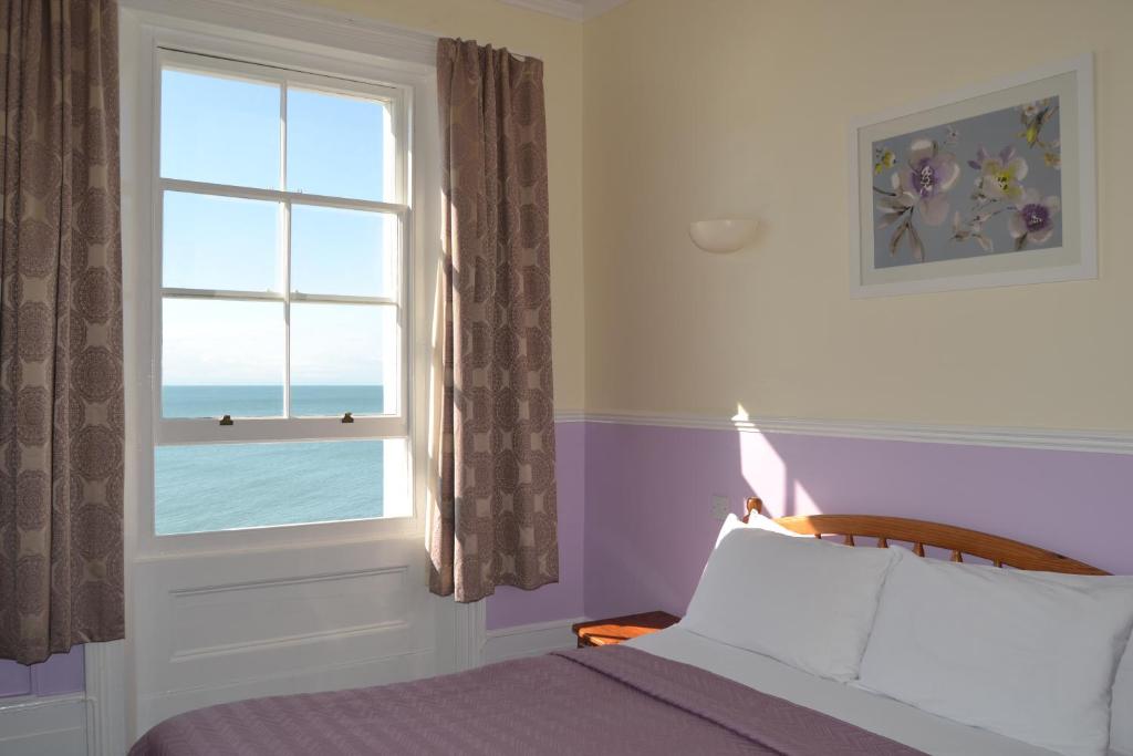 a bedroom with a bed and a window with the ocean at The Lindum in Hastings