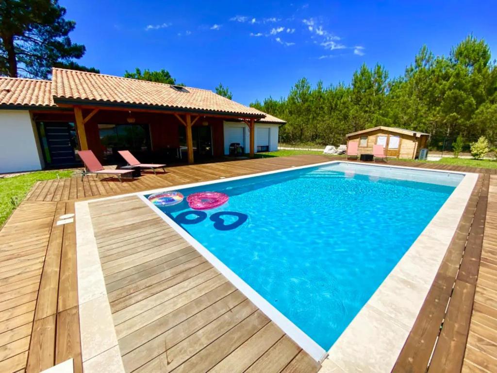 une piscine avec une terrasse en bois et une maison dans l'établissement VILLA CANTATE - Maison avec piscine, à Escource