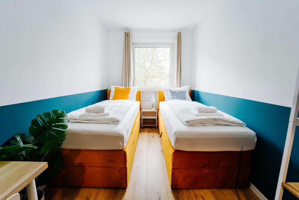 two beds in a small room with a window at Jenapartments for7 Boxspring & Smart TV & Waschmaschine in Jena