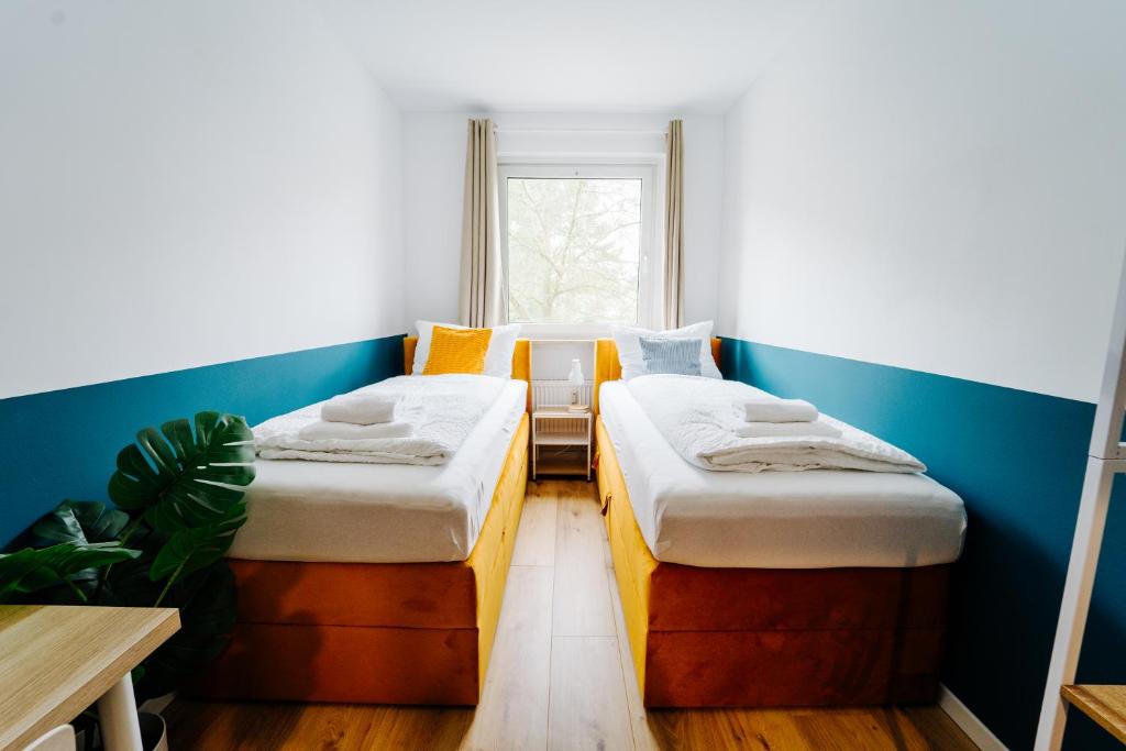 two beds in a small room with a window at Jenapartments for6 Boxspring & Smart TV & Waschmaschine in Jena