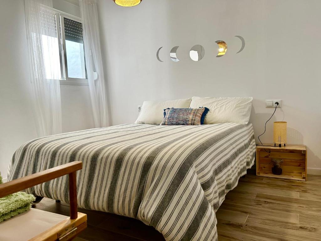 1 dormitorio con 1 cama con edredón a rayas y ventana en Apartamento Gades Conil C, en Conil de la Frontera