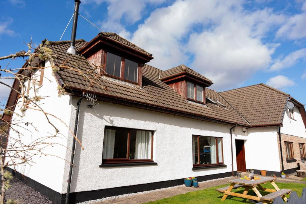 a white house with a picnic table in front of it at Barclay House Apartment in Fort William