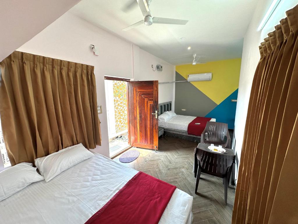 a bedroom with two beds and a table and a window at OM LINGESWARAN HOME STAY Tiruvannamalai in Tiruvannāmalai