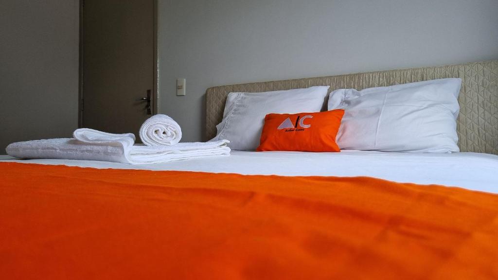 uma cama com uma almofada laranja e toalhas em Achei Casa Seu Espaço Exclusivo no Condomínio Lagoa Azul Topazio em Porto Velho
