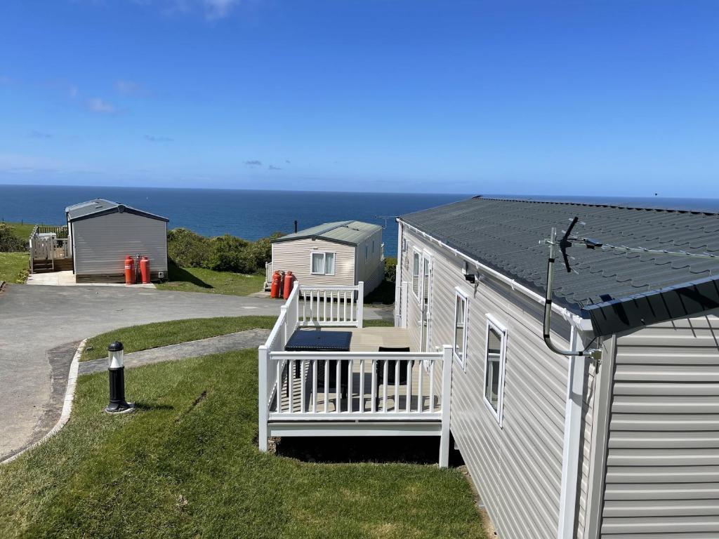 a small white house with a porch and the ocean at WH - Smugglers Cove 02 in Aberaeron