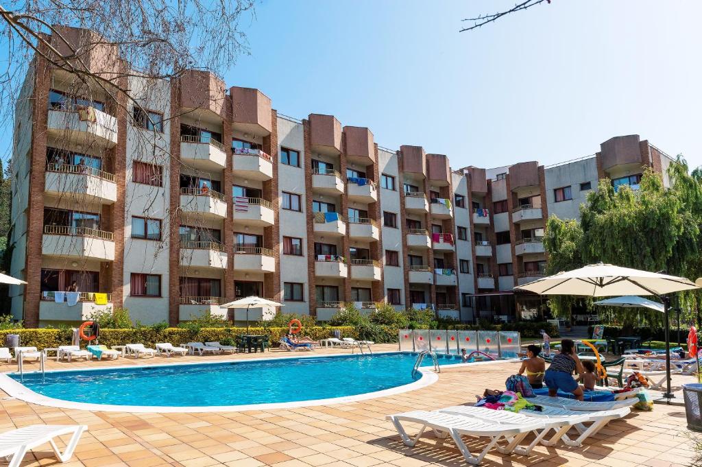 un hotel con piscina frente a un edificio en Aparthotel Las Mariposas en Lloret de Mar