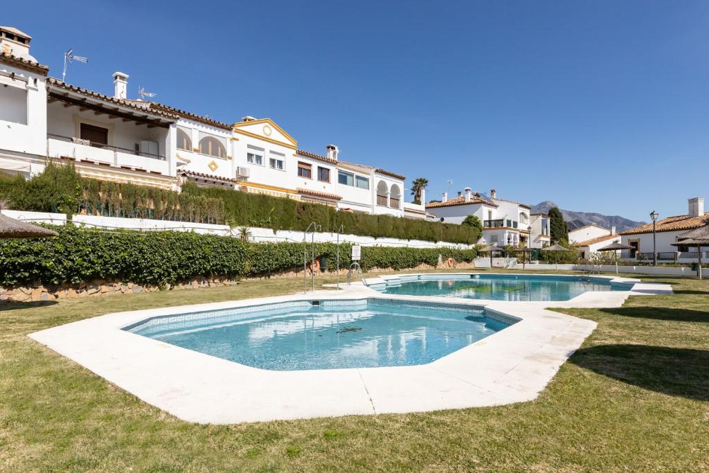 a swimming pool in the middle of a yard with houses at Casa Jardines del Sol J2 in Marbella
