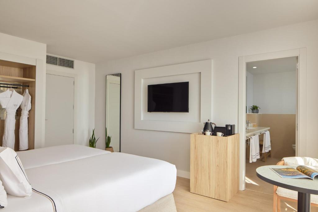 a white bedroom with a bed and a tv at Meliá Lloret de Mar in Lloret de Mar